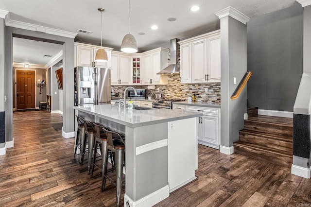 kitchen featuring wall chimney range hood, light countertops, visible vents, appliances with stainless steel finishes, and a sink