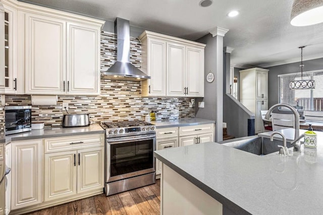 kitchen featuring ornamental molding, wall chimney exhaust hood, dark wood finished floors, stainless steel appliances, and a sink