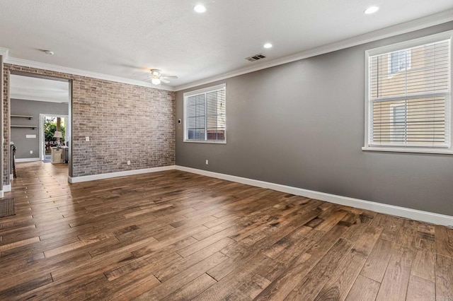 empty room featuring crown molding, ceiling fan, dark wood finished floors, and visible vents