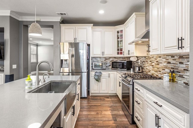 kitchen featuring pendant lighting, dark wood-style floors, wall chimney range hood, stainless steel appliances, and backsplash