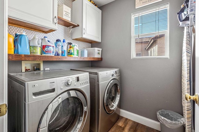 washroom featuring cabinet space, baseboards, washer and dryer, and dark wood-style floors