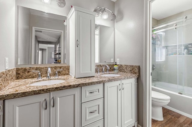 full bathroom featuring double vanity, a sink, toilet, and wood finished floors