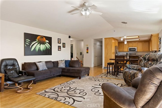 living room with light wood-style flooring, vaulted ceiling, and a ceiling fan