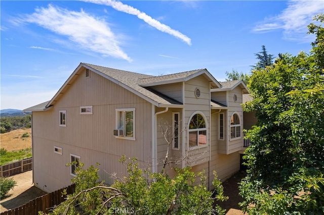 view of side of property featuring a shingled roof and fence