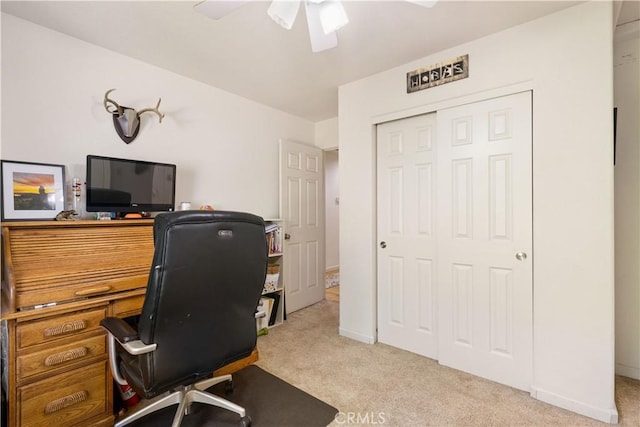 carpeted office space featuring baseboards and a ceiling fan
