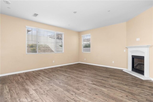 17938 Caraway Ct, San Bernardino, CA 92407 - unfurnished living room featuring wood finished floors, baseboards, a glass covered fireplace, and visible vents
