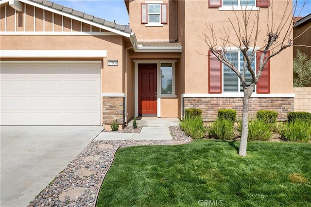 17938 Caraway Ct, San Bernardino, CA 92407 - view of exterior entry featuring concrete driveway, stone siding, a garage, and stucco siding