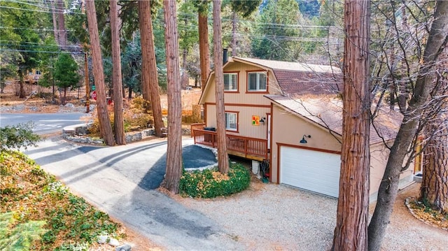 view of front facade featuring a chimney, a shingled roof, an attached garage, and gravel driveway