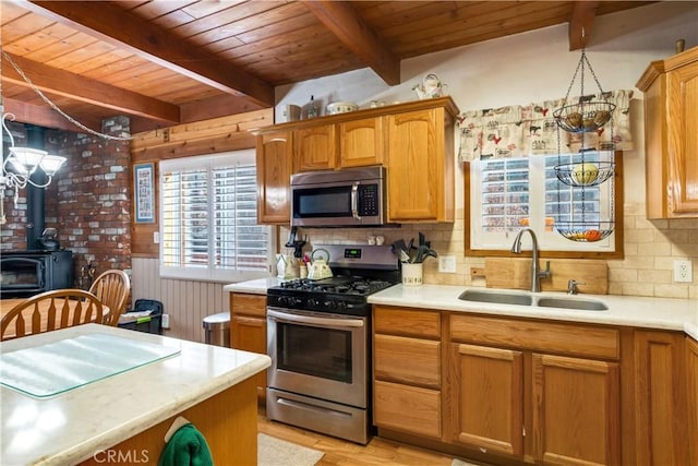 kitchen featuring appliances with stainless steel finishes, a sink, wooden ceiling, light countertops, and beamed ceiling