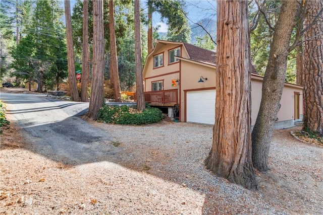 view of side of home featuring a garage and gravel driveway