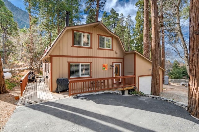 view of front of home featuring a garage, a wooden deck, and driveway