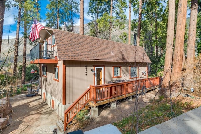 exterior space with a shingled roof and a balcony