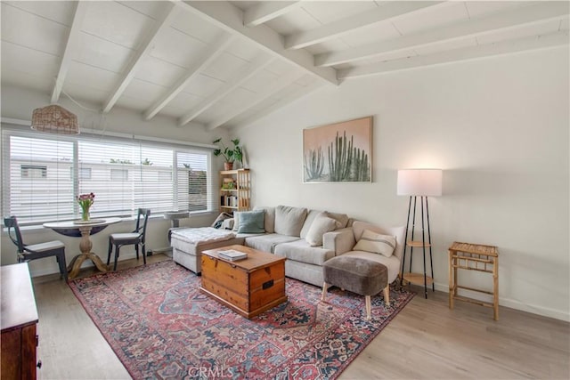 living area with wood finished floors, vaulted ceiling with beams, and baseboards