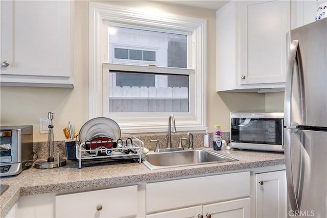 kitchen featuring white cabinets, light countertops, a sink, and appliances with stainless steel finishes