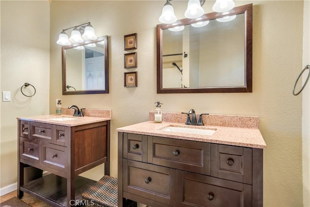 full bathroom with a sink, a textured wall, and two vanities