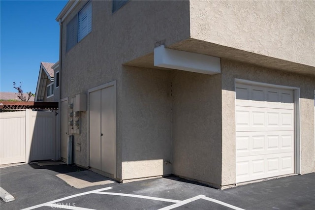 view of side of home with stucco siding, fence, and an attached garage