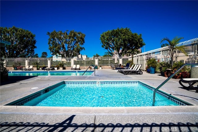 community pool with a patio area and fence