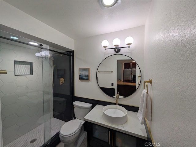bathroom featuring toilet, a stall shower, and vanity