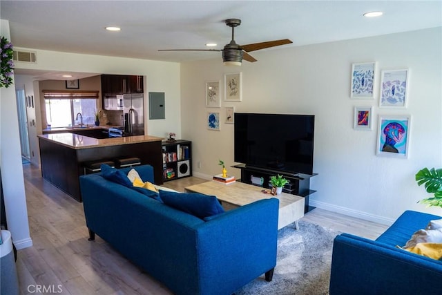 living room featuring recessed lighting, wood finished floors, a ceiling fan, and electric panel