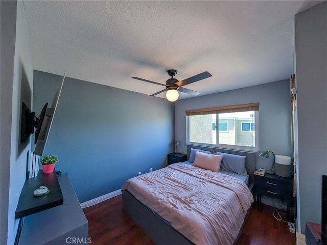 bedroom featuring a textured ceiling, wood finished floors, and baseboards