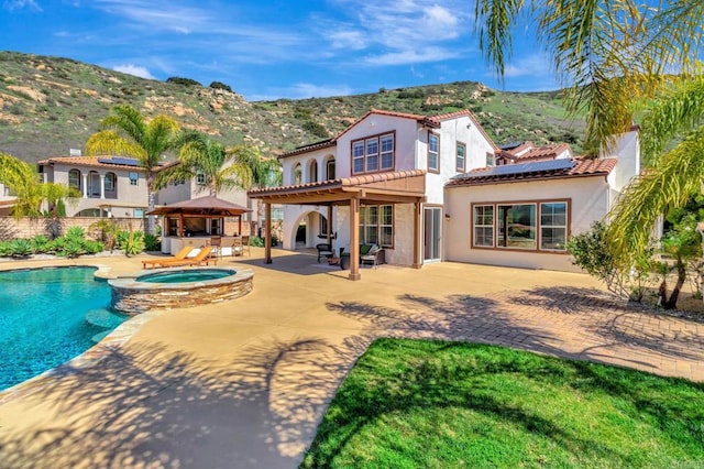back of house featuring stucco siding, a patio, fence, solar panels, and a mountain view