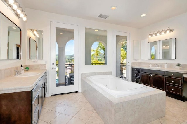 full bathroom featuring a sink, a whirlpool tub, two vanities, and tile patterned flooring