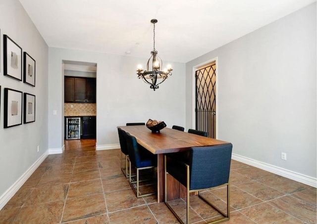 dining room with a chandelier, wine cooler, a bar, and baseboards