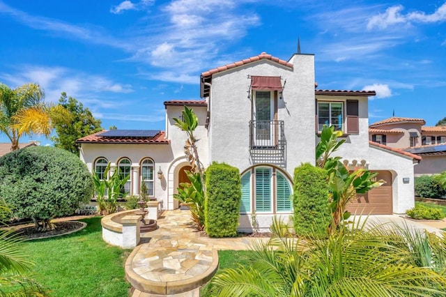 mediterranean / spanish home with stucco siding, solar panels, a tile roof, an attached garage, and concrete driveway
