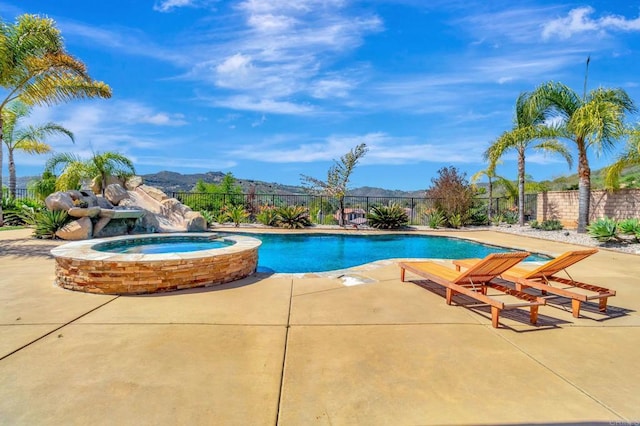 view of swimming pool with a patio, a mountain view, a pool with connected hot tub, and fence