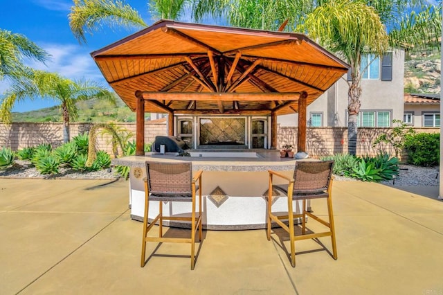 view of patio / terrace featuring a gazebo, fence, outdoor dry bar, and area for grilling