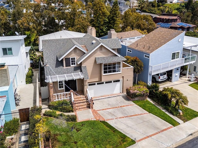 view of front of home with an attached garage, roof with shingles, driveway, and a residential view