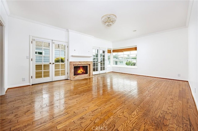 unfurnished living room with hardwood / wood-style floors, a high end fireplace, ornamental molding, and baseboards