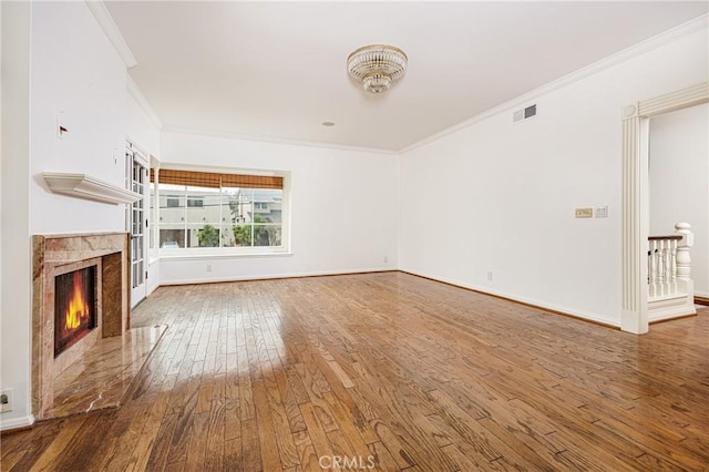 unfurnished living room featuring a high end fireplace, wood-type flooring, ornamental molding, and baseboards