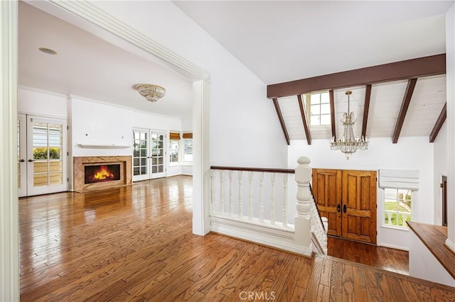 foyer entrance featuring a chandelier, a fireplace, lofted ceiling with beams, and hardwood / wood-style flooring