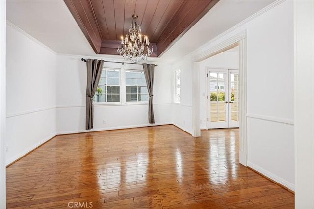 unfurnished dining area featuring a chandelier, wood-type flooring, a tray ceiling, and wood ceiling