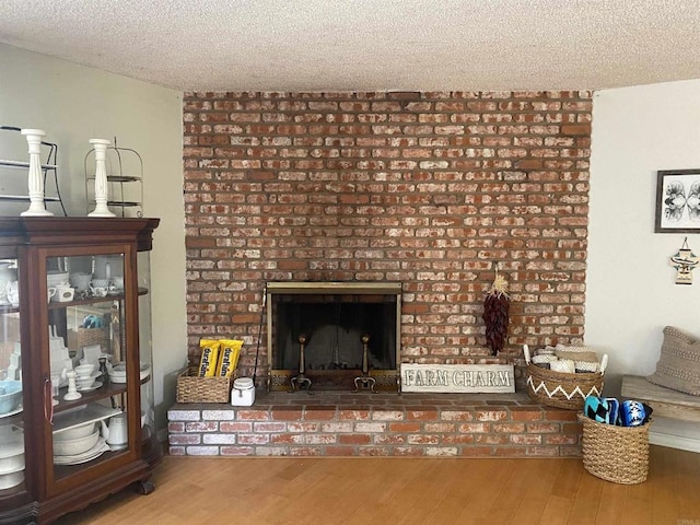 unfurnished living room featuring a textured ceiling, wood finished floors, and a fireplace