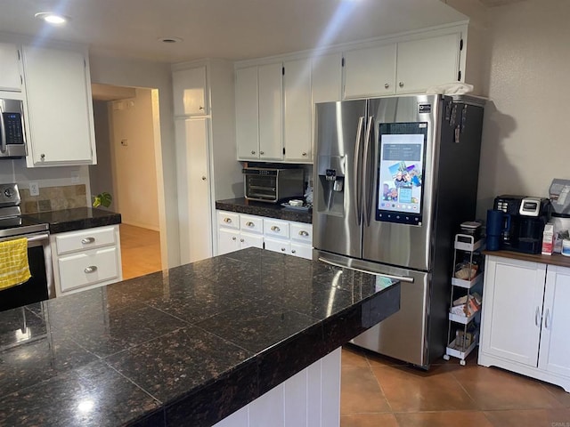 kitchen with a toaster, appliances with stainless steel finishes, white cabinets, and dark tile patterned floors