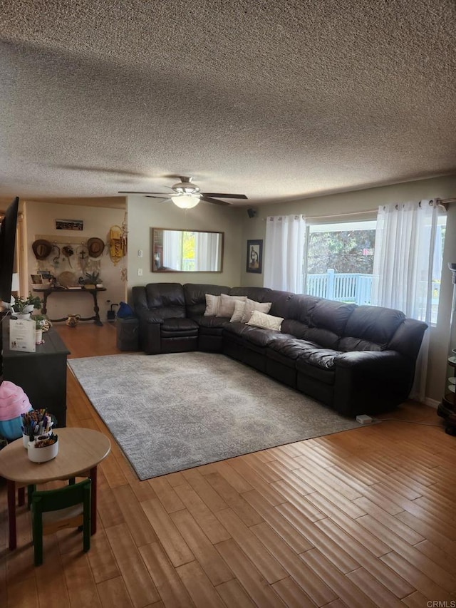 living room featuring a ceiling fan, a textured ceiling, and wood finished floors