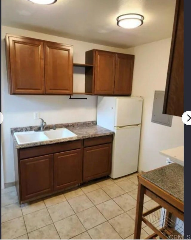 kitchen with a sink, open shelves, light tile patterned flooring, and freestanding refrigerator