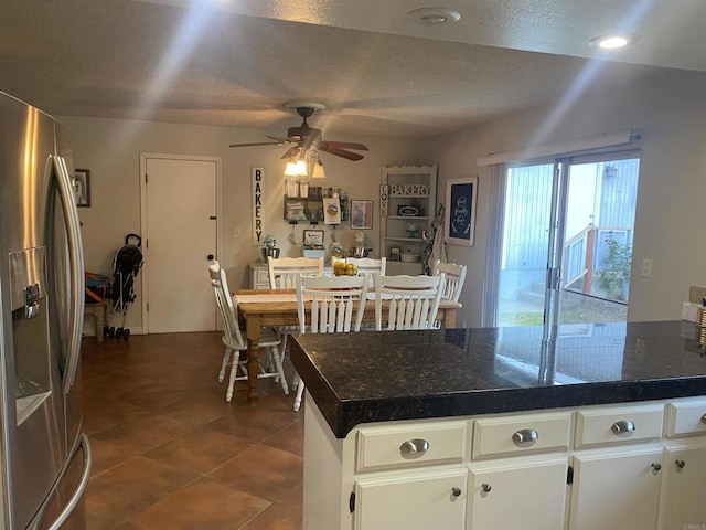 kitchen with dark tile patterned flooring, stainless steel fridge with ice dispenser, tile counters, and a ceiling fan