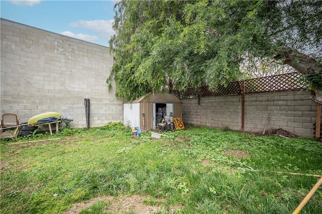 view of yard with a storage unit, a fenced backyard, and an outdoor structure