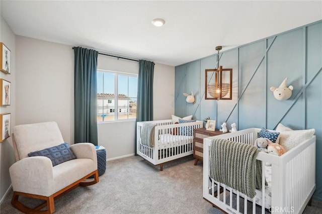 carpeted bedroom featuring baseboards and a crib