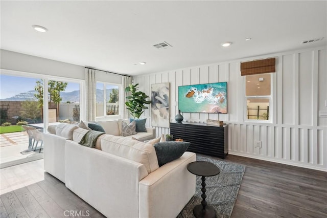 living room featuring a decorative wall, visible vents, recessed lighting, and wood finished floors