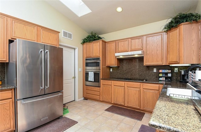 24182 Via Llano, Murrieta, CA 92562 - kitchen featuring appliances with stainless steel finishes, under cabinet range hood, a skylight, tasteful backsplash, and lofted ceiling