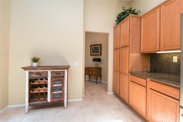 24182 Via Llano, Murrieta, CA 92562 - kitchen featuring tasteful backsplash, dark stone counters, light tile patterned floors, and baseboards