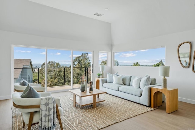 living room with baseboards, a towering ceiling, wood finished floors, and visible vents