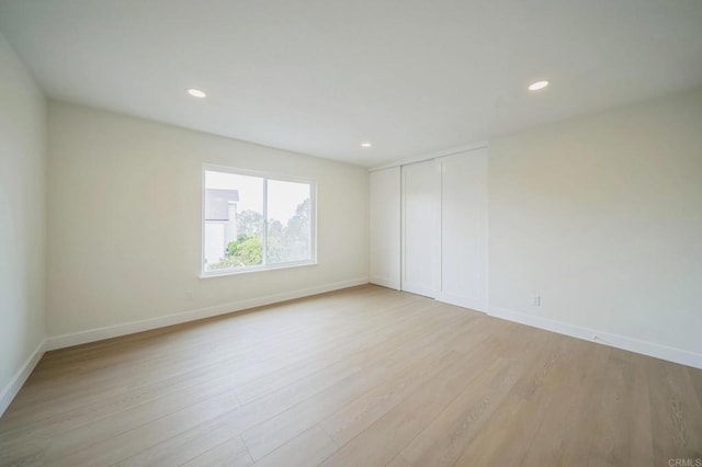 spare room featuring recessed lighting, light wood-style floors, and baseboards