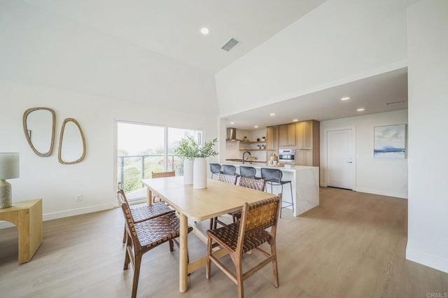 dining space featuring high vaulted ceiling, light wood-style flooring, visible vents, recessed lighting, and baseboards