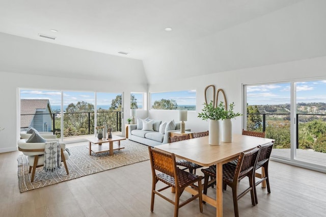 dining space featuring vaulted ceiling, visible vents, a wealth of natural light, and light wood-style flooring