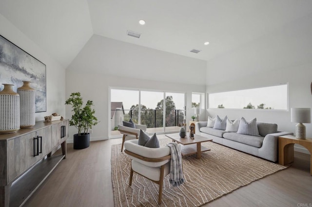 living room with visible vents, a wealth of natural light, and vaulted ceiling